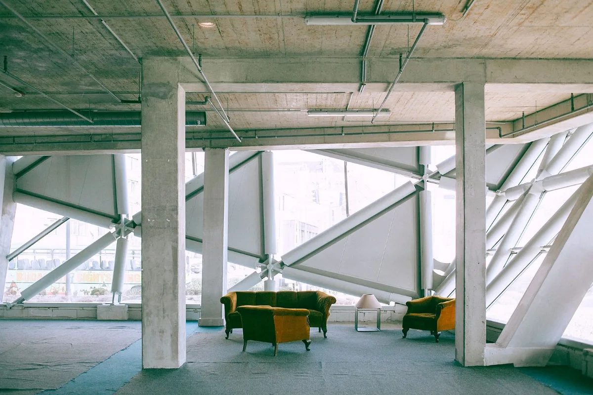Interior de concreto con sillones y estructura metálica.